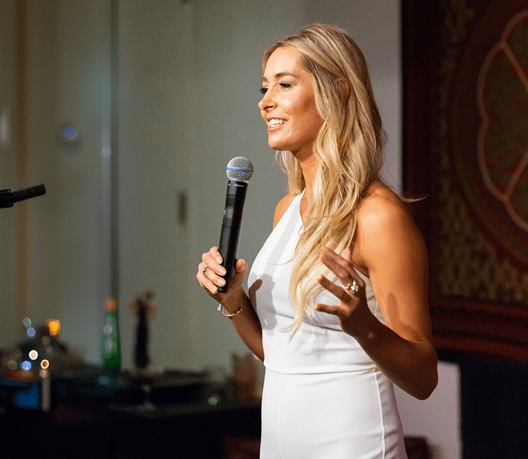 Danette speaking on stage with a microphone.